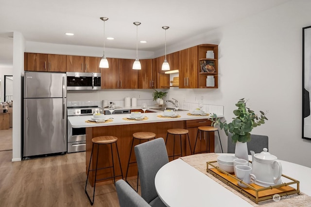 kitchen featuring sink, stainless steel appliances, hanging light fixtures, and a kitchen bar