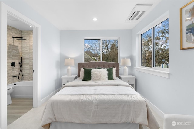 bedroom with light hardwood / wood-style floors, connected bathroom, and multiple windows