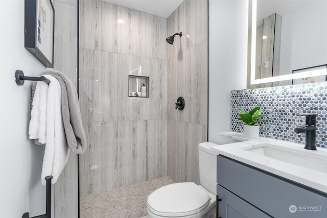 bathroom with toilet, a shower, vanity, and decorative backsplash