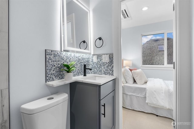 bathroom with toilet, vanity, and backsplash