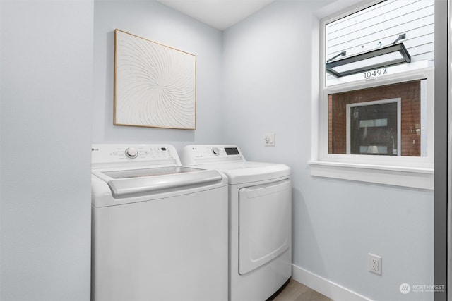 clothes washing area featuring washer and clothes dryer, a healthy amount of sunlight, and light hardwood / wood-style flooring