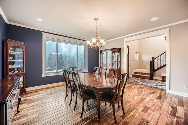 dining room with light wood-style floors, ornamental molding, baseboards, and stairs