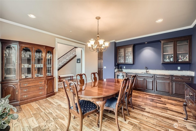 dining room featuring light wood-style floors, a notable chandelier, and crown molding