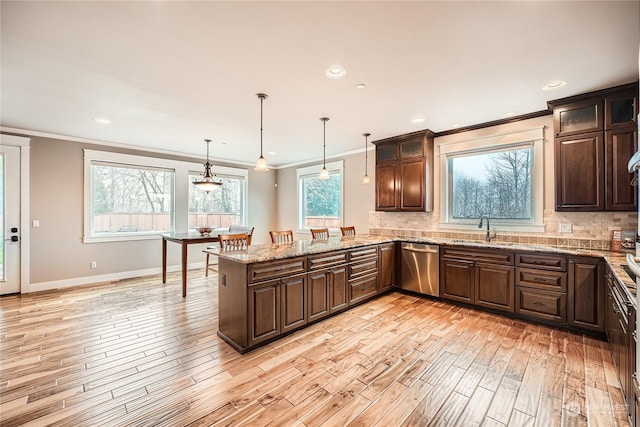 kitchen with tasteful backsplash, dark brown cabinetry, dishwasher, and a sink