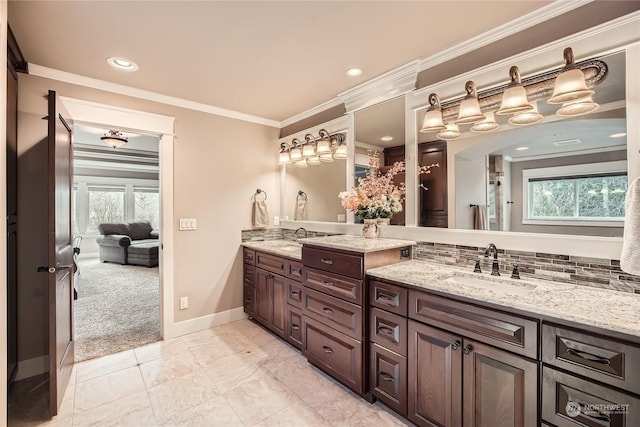 bathroom featuring double vanity, plenty of natural light, ornamental molding, and a sink