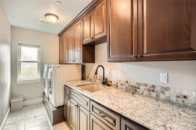 laundry area with cabinet space, visible vents, washing machine and dryer, a sink, and baseboards