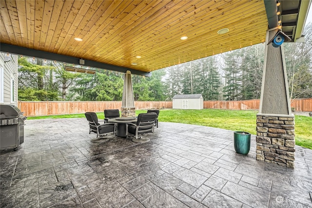 view of patio featuring an outdoor fire pit, a fenced backyard, an outbuilding, a grill, and a storage unit