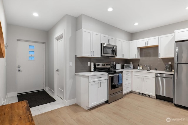 kitchen featuring backsplash, stainless steel appliances, sink, and white cabinets