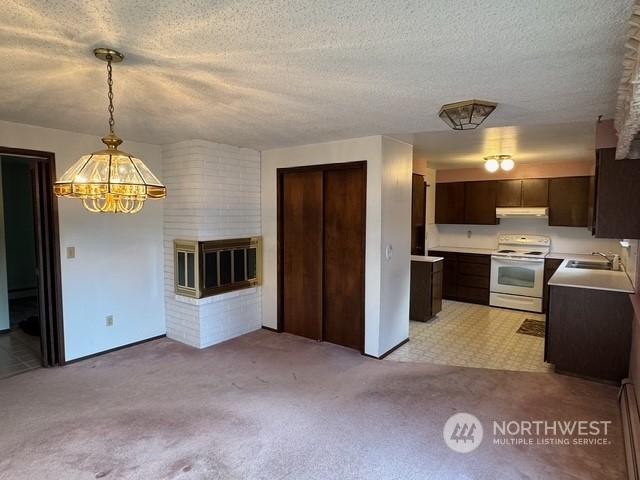 kitchen with electric stove, pendant lighting, a notable chandelier, light colored carpet, and sink