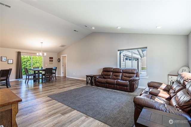 living room with an inviting chandelier, vaulted ceiling, and wood-type flooring