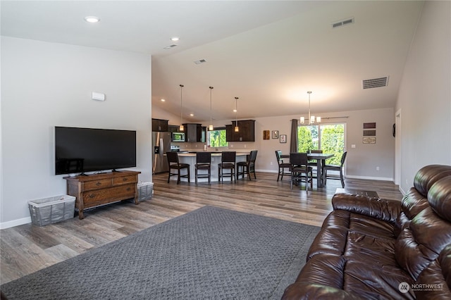 living room with a chandelier, vaulted ceiling, and wood-type flooring