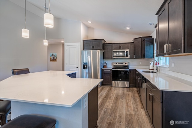 kitchen featuring pendant lighting, stainless steel appliances, a kitchen island, a breakfast bar area, and sink