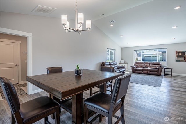 dining area featuring lofted ceiling, hardwood / wood-style flooring, and a notable chandelier