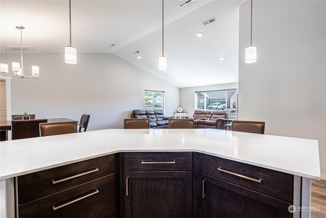 kitchen with kitchen peninsula, a chandelier, hanging light fixtures, lofted ceiling, and light wood-type flooring