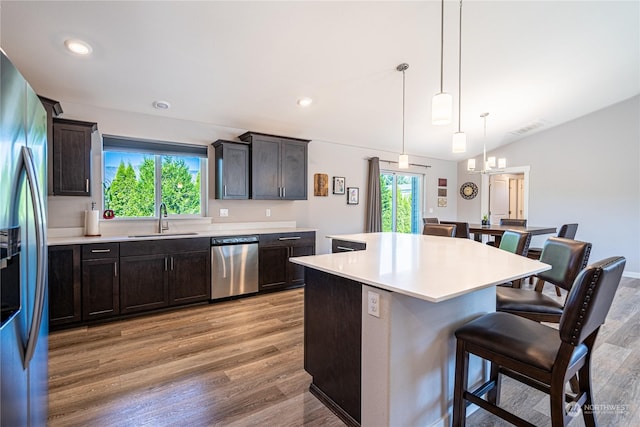 kitchen featuring decorative light fixtures, stainless steel appliances, a kitchen bar, a kitchen island, and sink