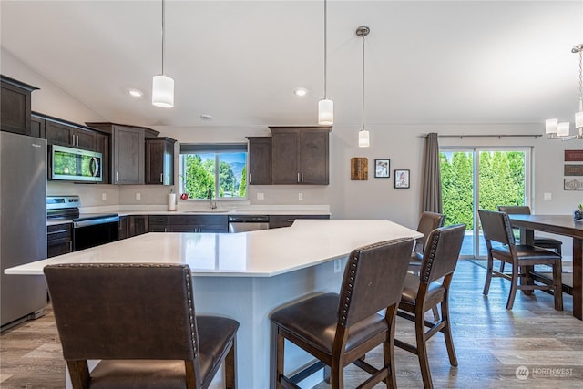 kitchen with sink, a center island, light hardwood / wood-style floors, pendant lighting, and appliances with stainless steel finishes