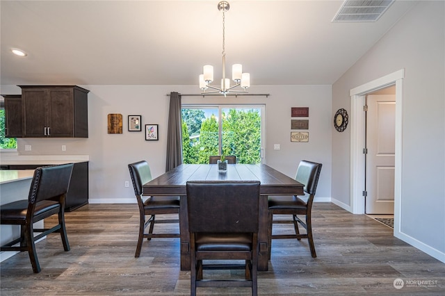 dining room featuring an inviting chandelier, vaulted ceiling, and dark wood-type flooring