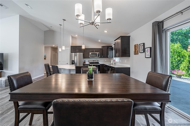 dining room with a notable chandelier, vaulted ceiling, light hardwood / wood-style floors, and sink