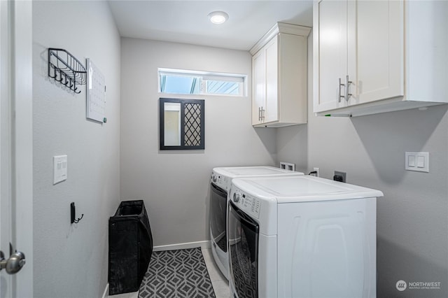 clothes washing area featuring washing machine and dryer, light tile patterned flooring, and cabinets