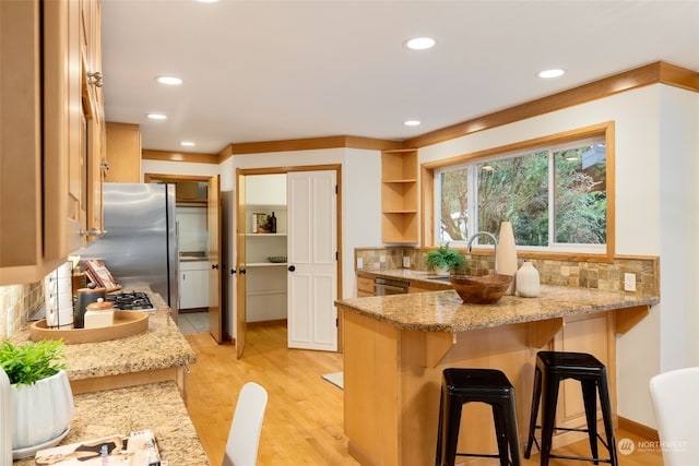 kitchen with light stone counters, appliances with stainless steel finishes, a kitchen breakfast bar, and sink