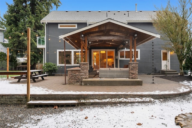 snow covered rear of property with a patio