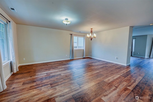 spare room featuring an inviting chandelier and hardwood / wood-style flooring