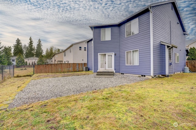 rear view of property featuring cooling unit and a yard