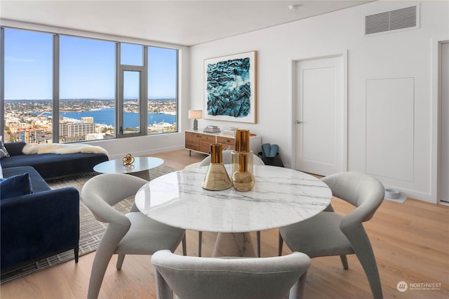 dining room with light hardwood / wood-style floors and a water view