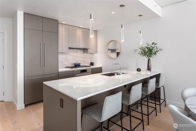 kitchen featuring kitchen peninsula, pendant lighting, tasteful backsplash, a kitchen bar, and gray cabinets