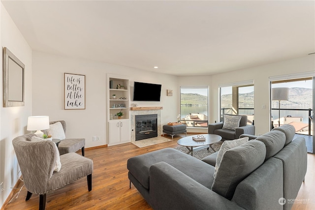 living room with a tile fireplace, hardwood / wood-style flooring, and built in features