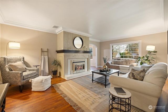 living room with a tile fireplace, ornamental molding, and hardwood / wood-style flooring