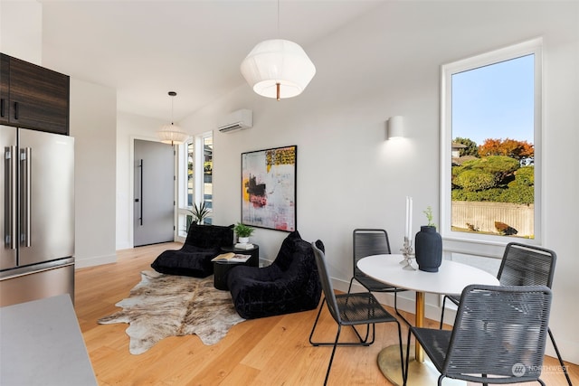 dining area featuring light wood-type flooring and an AC wall unit