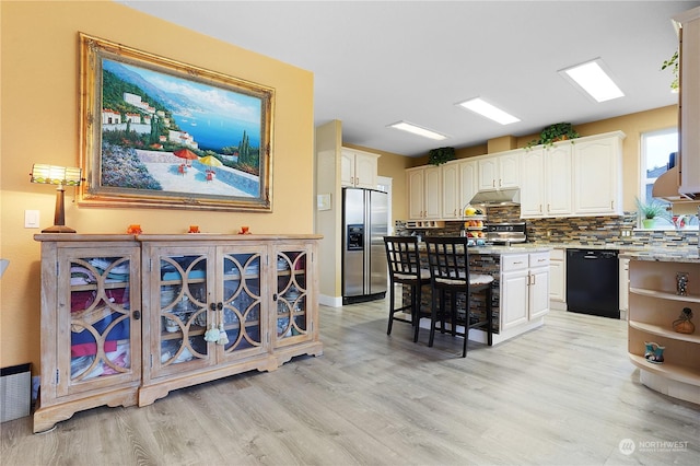 kitchen with light hardwood / wood-style floors, stainless steel refrigerator with ice dispenser, backsplash, dishwasher, and light stone counters