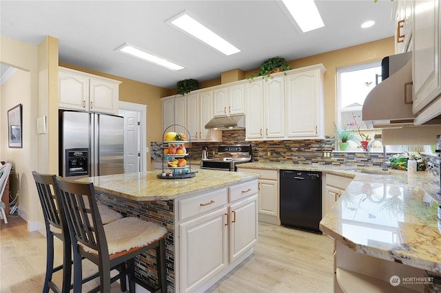 kitchen featuring a kitchen island, white cabinetry, stainless steel appliances, sink, and light stone counters