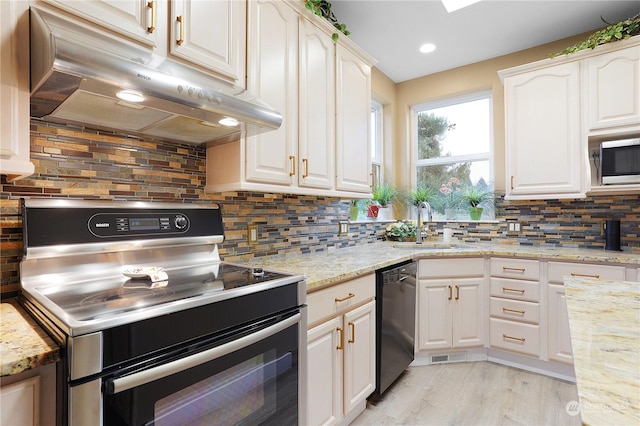 kitchen featuring light stone counters, white cabinets, decorative backsplash, and stainless steel appliances