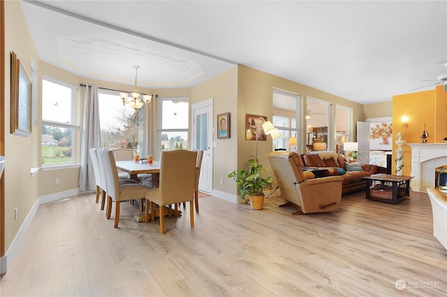 dining space featuring ceiling fan with notable chandelier, light wood-type flooring, and a fireplace