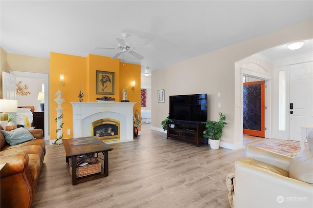 living room featuring ceiling fan, a fireplace, and light hardwood / wood-style flooring