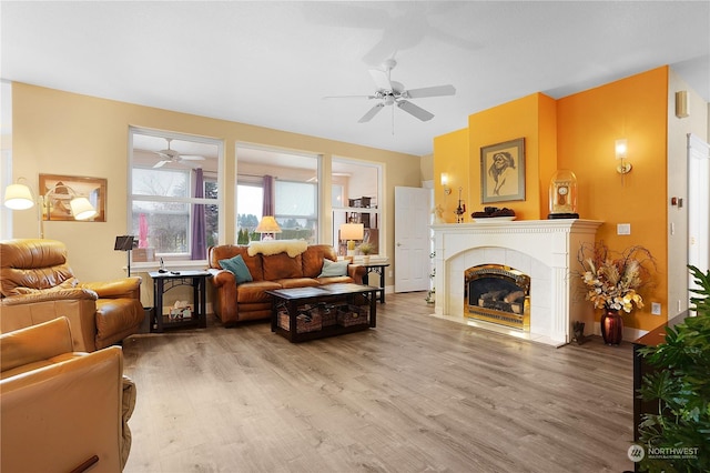 living room with ceiling fan, wood-type flooring, and a tiled fireplace