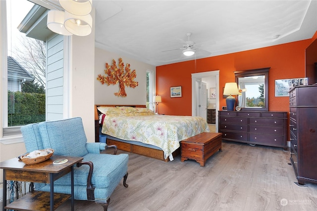 bedroom featuring ceiling fan, ensuite bathroom, and light hardwood / wood-style flooring