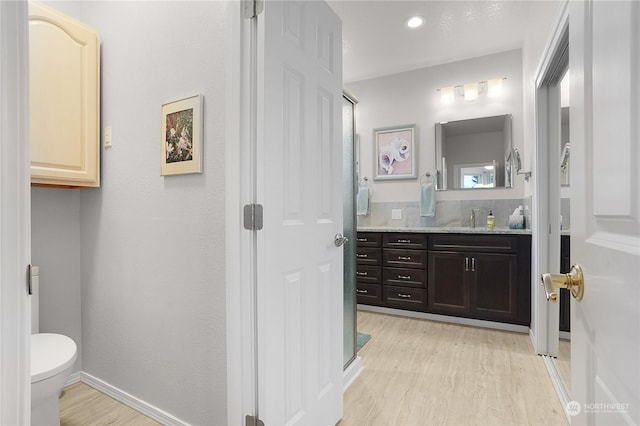 bathroom featuring backsplash, hardwood / wood-style floors, toilet, and vanity