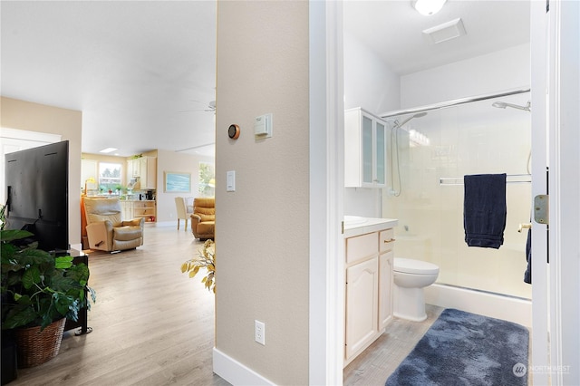 bathroom with toilet, hardwood / wood-style floors, a shower with door, ceiling fan, and vanity