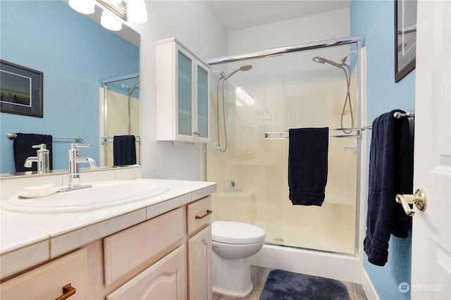 bathroom featuring toilet, an enclosed shower, and vanity