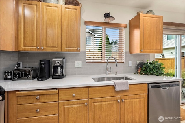 kitchen featuring dishwasher, light countertops, tasteful backsplash, and a sink