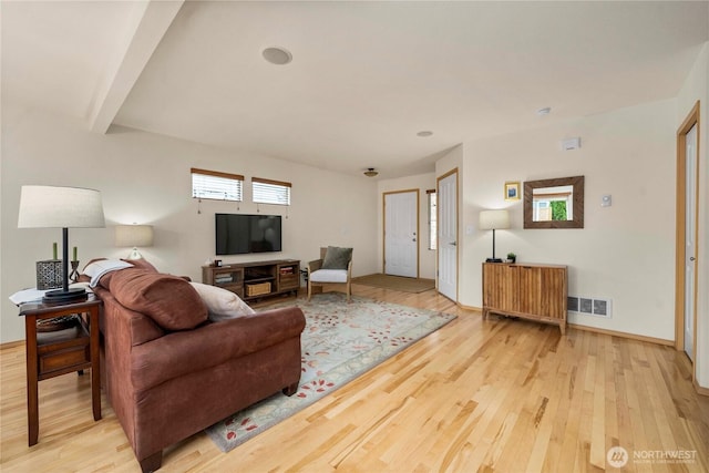 living area featuring visible vents, light wood-style flooring, baseboards, and beamed ceiling