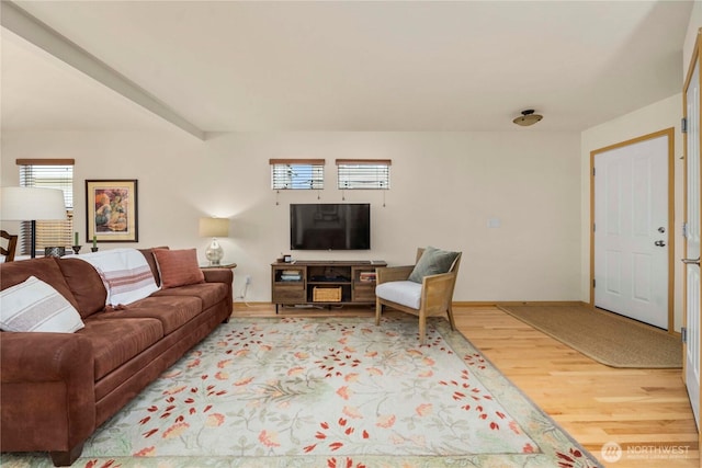 living area featuring beamed ceiling, light wood-style floors, and baseboards