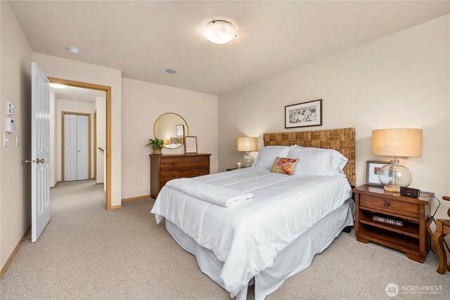 bedroom with baseboards and light carpet