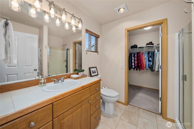 full bathroom featuring a spacious closet, baseboards, toilet, a stall shower, and vanity