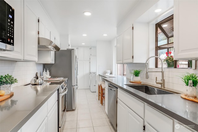 kitchen with white cabinetry, stainless steel appliances, sink, backsplash, and light tile patterned flooring