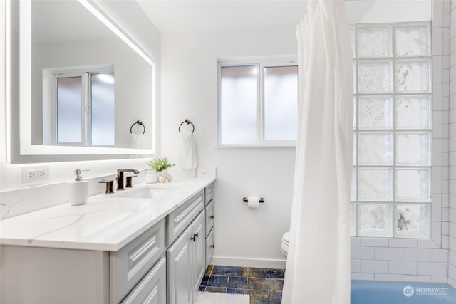 bathroom featuring toilet, vanity, and plenty of natural light