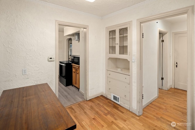 hallway featuring a textured ceiling, ornamental molding, and light hardwood / wood-style flooring